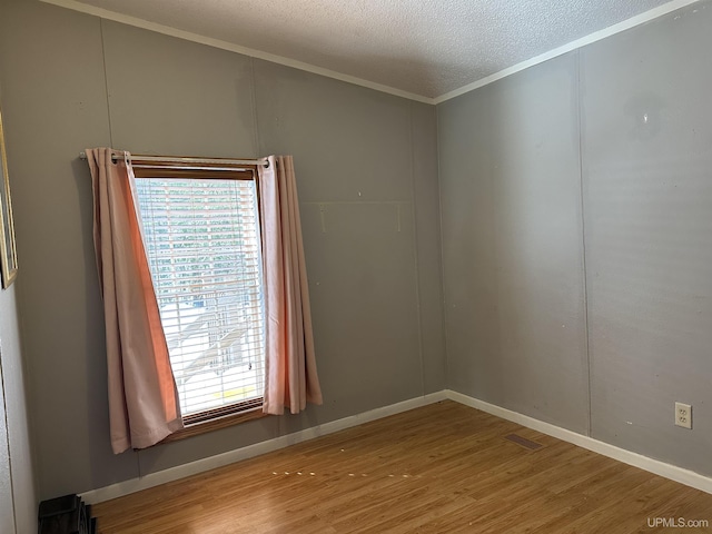 unfurnished room featuring ornamental molding, a textured ceiling, baseboards, and wood finished floors