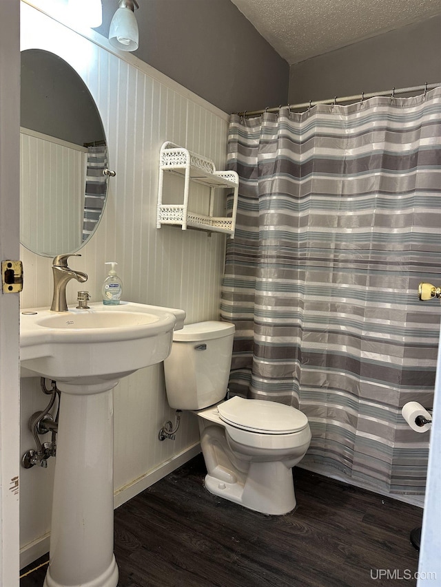 full bath featuring a shower with curtain, toilet, a sink, a textured ceiling, and wood finished floors