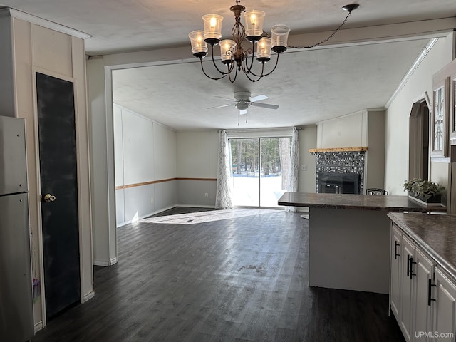 kitchen with dark countertops, dark wood-style floors, ceiling fan with notable chandelier, and a fireplace