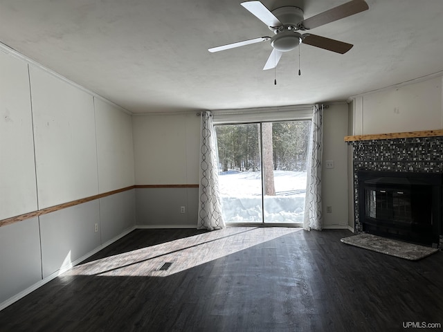 unfurnished living room with a tiled fireplace, wood finished floors, and ceiling fan