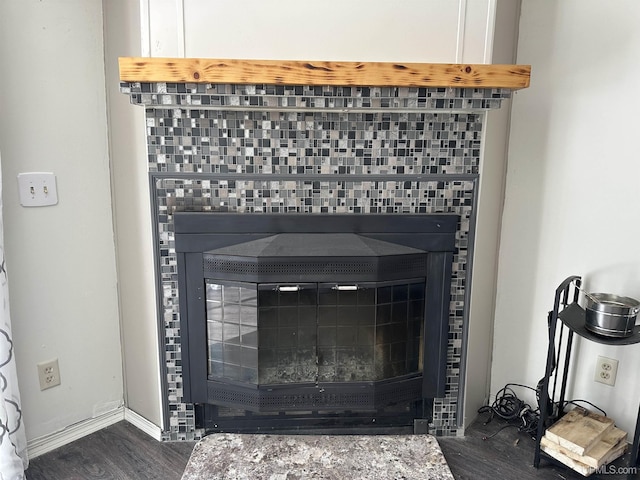 room details with baseboards, wood finished floors, and a tiled fireplace