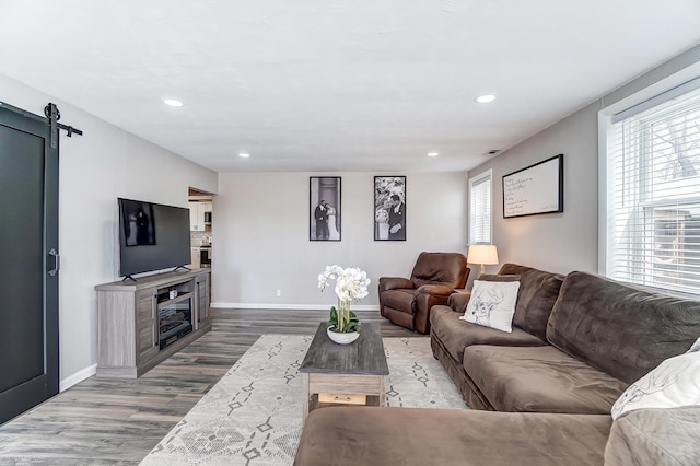 living room featuring a barn door, recessed lighting, wood finished floors, and baseboards