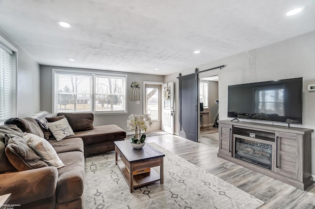 living area with recessed lighting, baseboards, light wood-type flooring, and a barn door