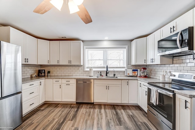 kitchen featuring light countertops, light wood finished floors, appliances with stainless steel finishes, and a sink