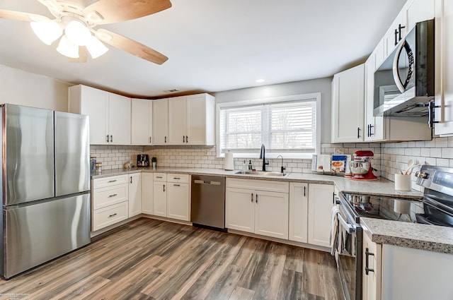 kitchen featuring a sink, white cabinets, wood finished floors, and stainless steel appliances