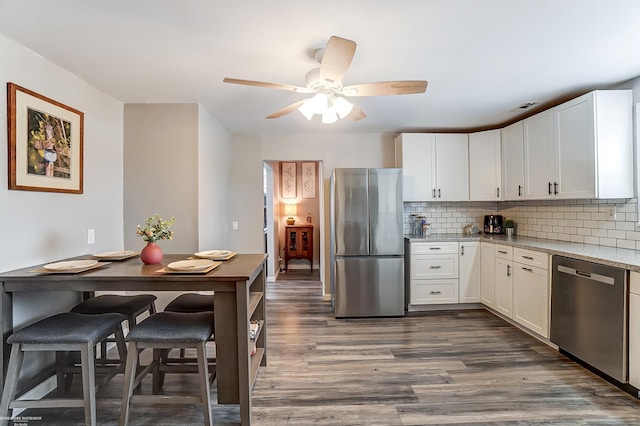 kitchen featuring decorative backsplash, dark wood-style flooring, white cabinetry, and stainless steel appliances