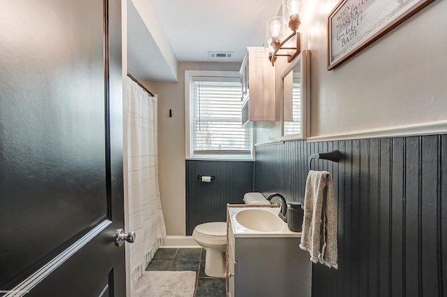 bathroom with vanity, visible vents, a wainscoted wall, wood walls, and toilet