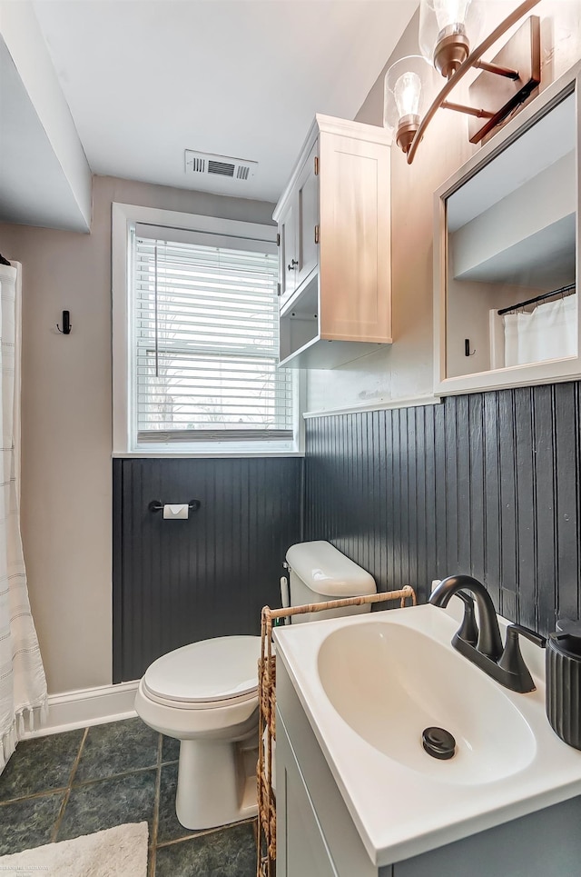 bathroom with visible vents, a wainscoted wall, toilet, wood walls, and vanity