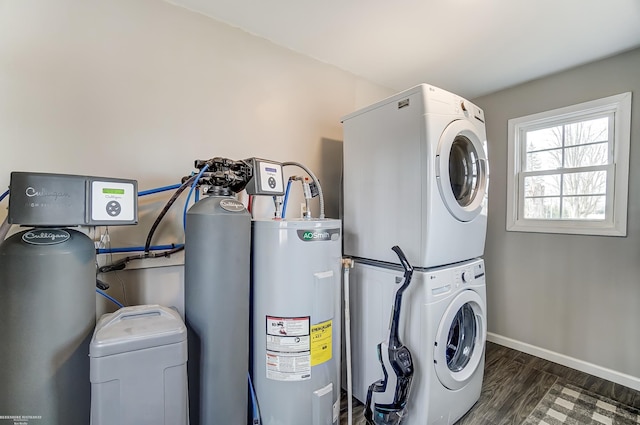 laundry room featuring wood finished floors, baseboards, laundry area, stacked washer / drying machine, and electric water heater