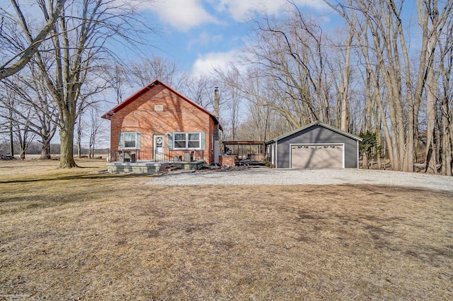 view of front of property featuring an outbuilding, a front yard, a detached garage, and brick siding