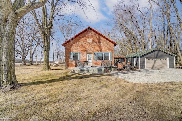 view of front of property with an outbuilding, a front yard, driveway, a garage, and brick siding