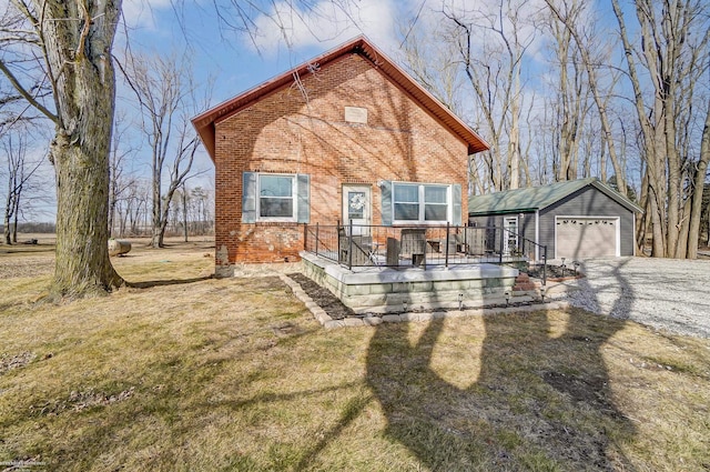 view of front of house featuring brick siding, a detached garage, an outbuilding, and a front lawn