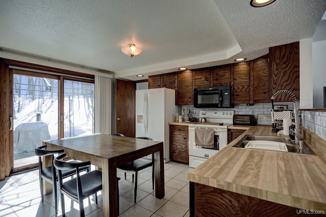 kitchen featuring butcher block countertops, light tile patterned floors, white appliances, a textured ceiling, and a sink