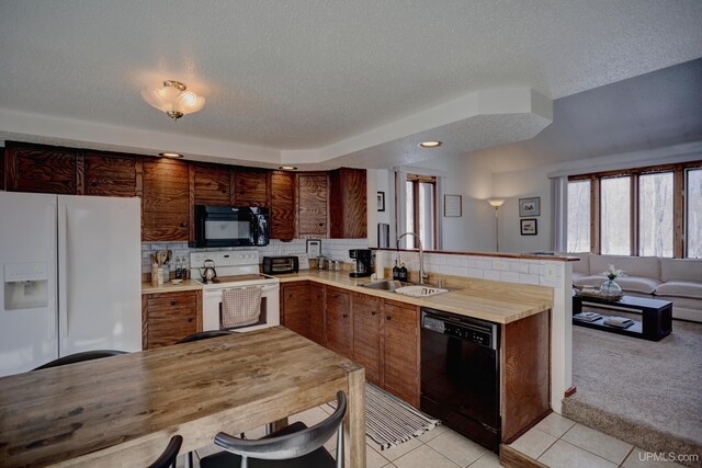 kitchen featuring light colored carpet, light countertops, a peninsula, black appliances, and a sink