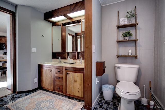 bathroom with double vanity, toilet, baseboards, and a sink