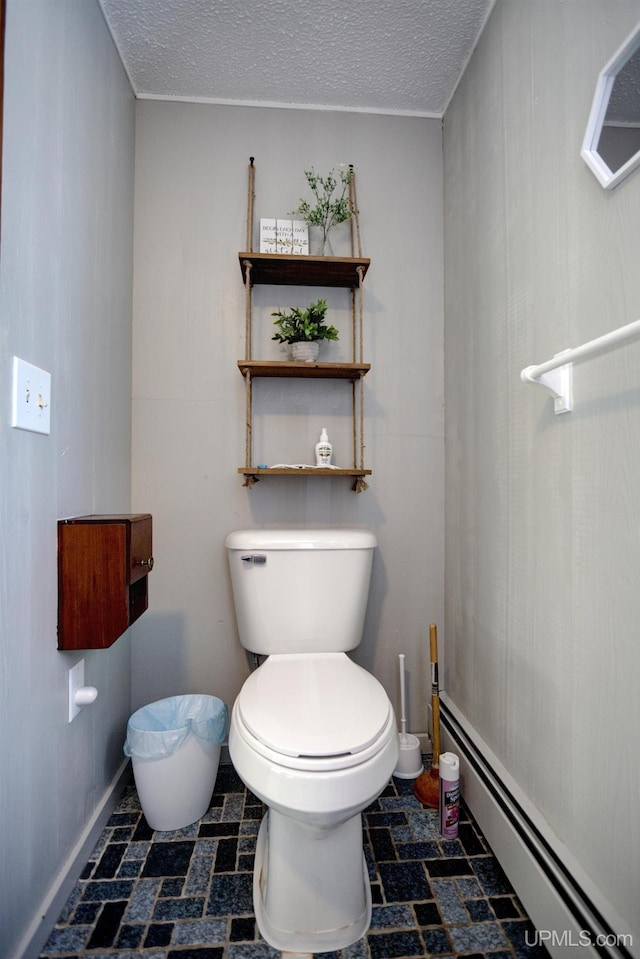 half bathroom featuring a baseboard heating unit, baseboards, toilet, and a textured ceiling