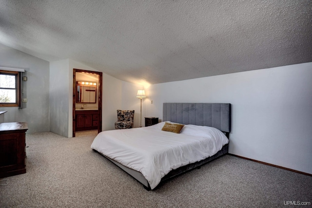 carpeted bedroom featuring ensuite bath, a textured ceiling, baseboards, and vaulted ceiling