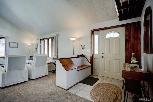 entrance foyer featuring light tile patterned floors, a textured ceiling, and vaulted ceiling