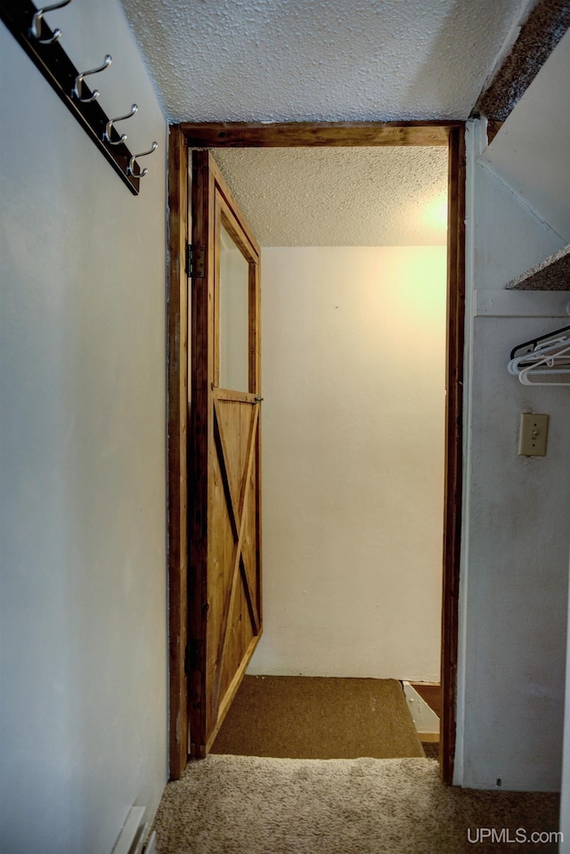 corridor with carpet floors and a textured ceiling