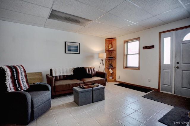 living room featuring light tile patterned flooring, a paneled ceiling, and baseboards