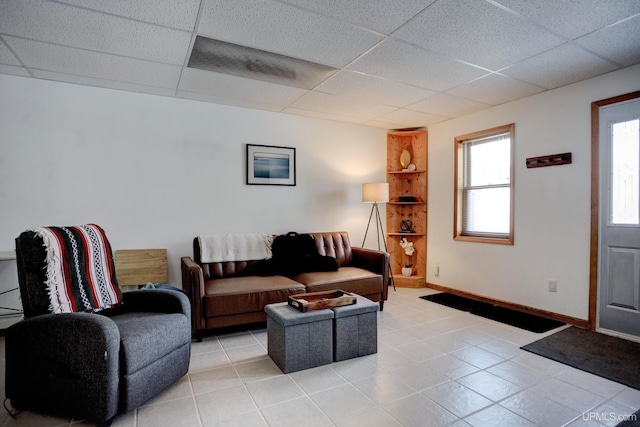 living room featuring light tile patterned flooring, a paneled ceiling, and baseboards