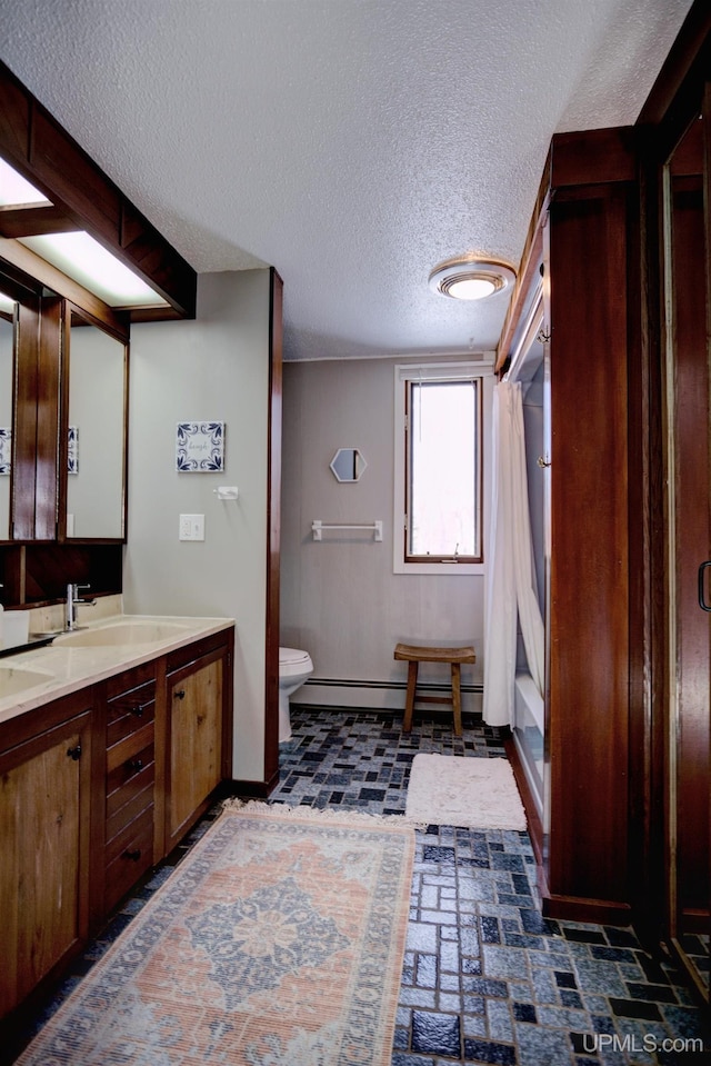 full bathroom with baseboards, toilet, brick floor, vanity, and a baseboard radiator