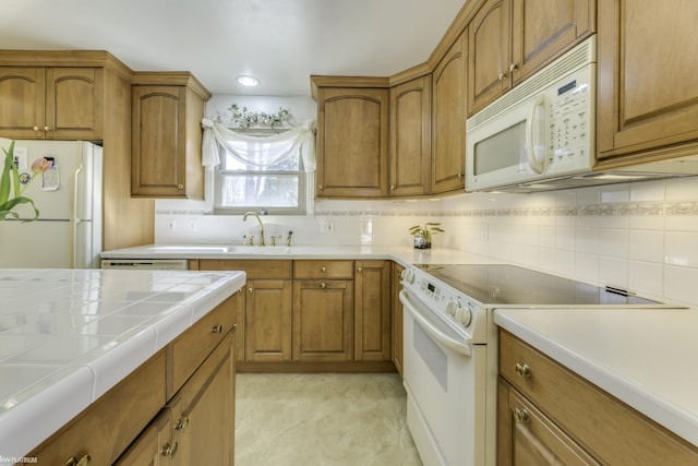 kitchen featuring backsplash, brown cabinets, and white appliances