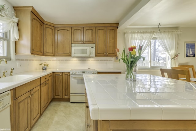 kitchen featuring tile counters, white appliances, a wealth of natural light, and a sink