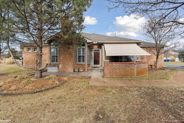 view of front facade with brick siding and a front yard