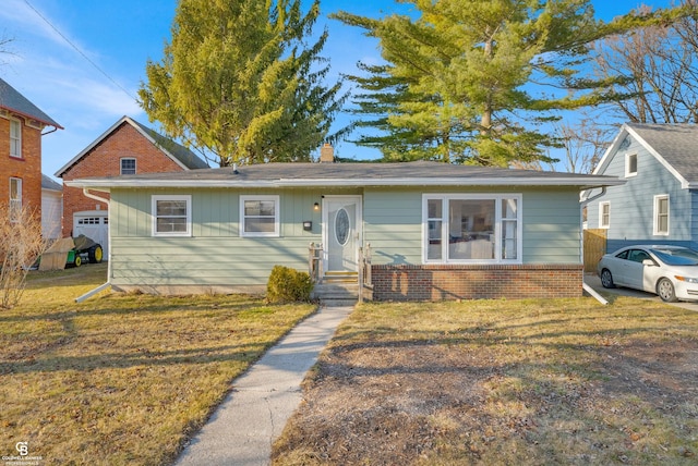 bungalow-style house with brick siding, a chimney, and a front yard