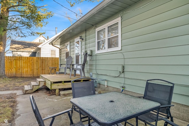 view of patio with outdoor dining space, a wooden deck, and fence