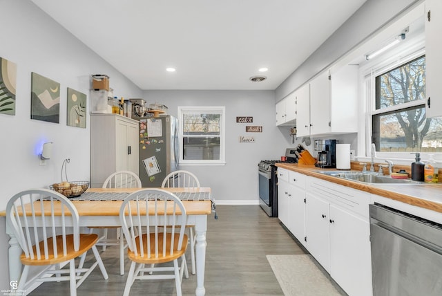 kitchen with a wealth of natural light, white cabinets, appliances with stainless steel finishes, and a sink