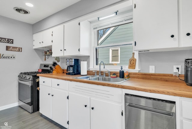 kitchen with visible vents, light wood-type flooring, stainless steel appliances, white cabinetry, and a sink