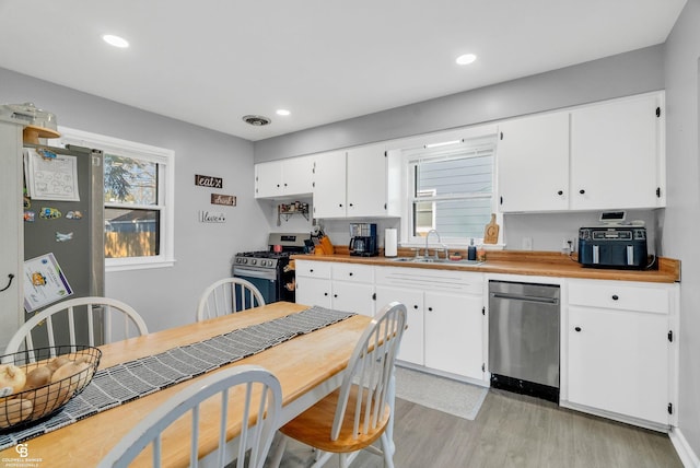 kitchen featuring light wood-type flooring, a sink, white cabinetry, recessed lighting, and stainless steel appliances