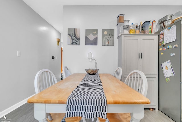 dining space with baseboards and light wood-style floors