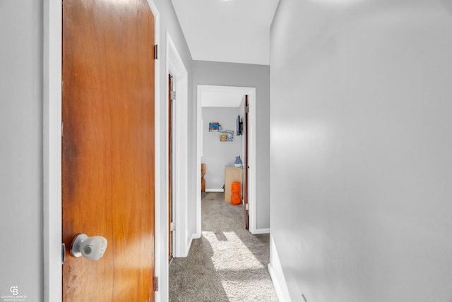 hallway featuring carpet flooring and baseboards