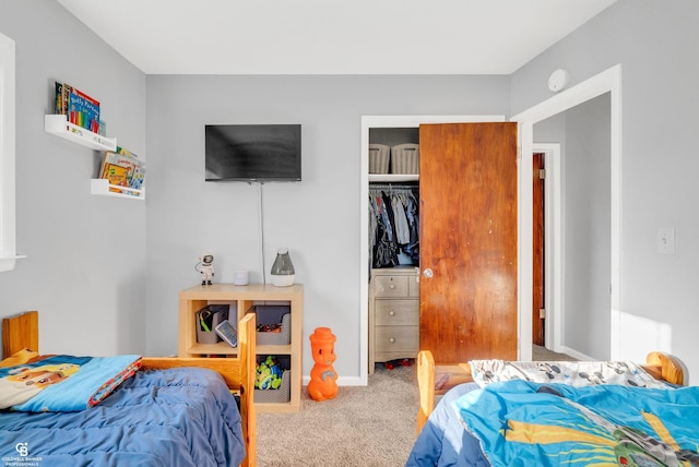 carpeted bedroom with a closet and baseboards