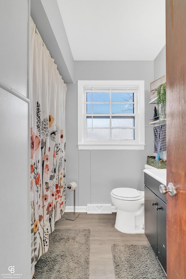 bathroom with vanity, wood finished floors, visible vents, baseboards, and toilet