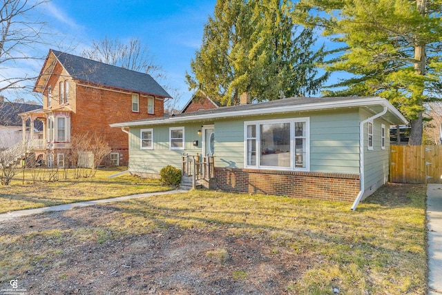 view of front of home with a front yard, brick siding, a chimney, and fence