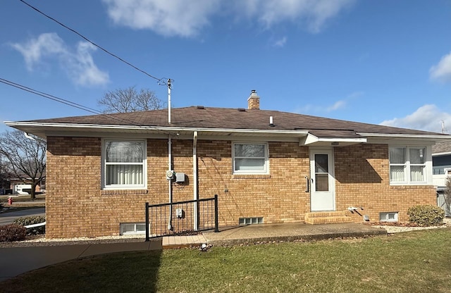 view of front of property featuring a chimney, entry steps, a front lawn, a patio area, and brick siding