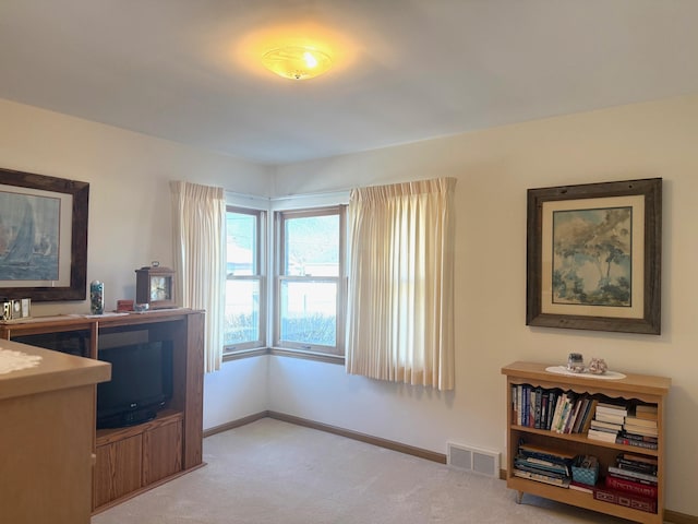 interior space featuring visible vents, light colored carpet, and baseboards