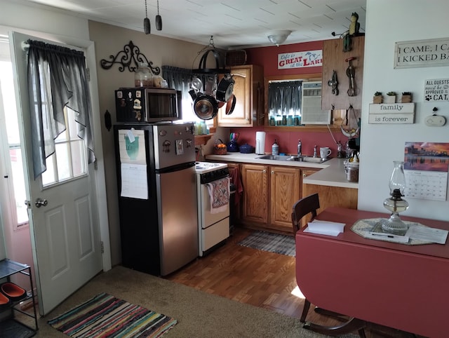 kitchen with brown cabinets, a sink, dark wood-style floors, stainless steel appliances, and light countertops