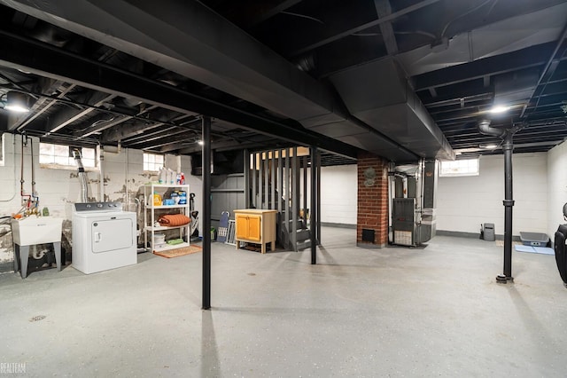 basement with heating unit, washer / clothes dryer, and a sink