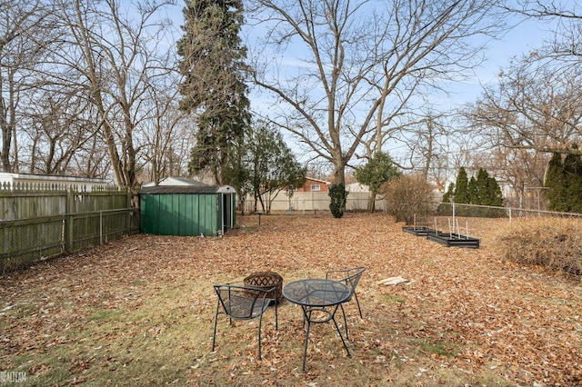 view of yard with an outdoor structure, a storage unit, a fenced backyard, and a fire pit