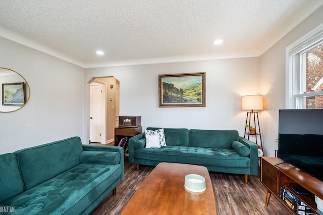 living area featuring dark wood finished floors, recessed lighting, arched walkways, and a textured ceiling