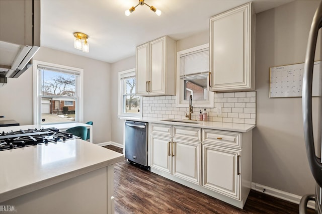 kitchen featuring stainless steel dishwasher, dark wood-type flooring, backsplash, and a sink