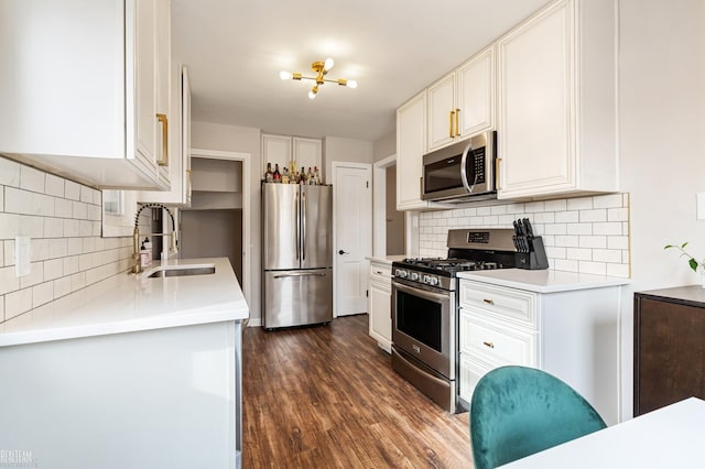 kitchen featuring tasteful backsplash, dark wood-type flooring, light countertops, appliances with stainless steel finishes, and a sink