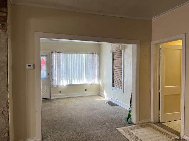 empty room with visible vents, baseboards, carpet flooring, and crown molding