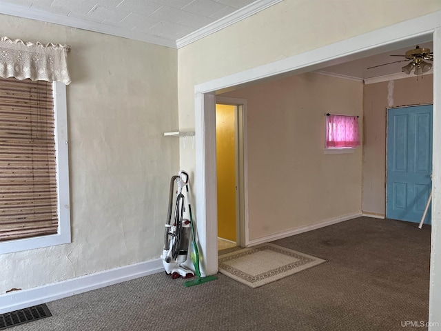 carpeted spare room with ceiling fan, visible vents, baseboards, and ornamental molding