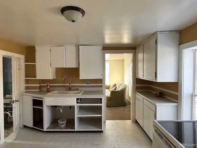 kitchen with open shelves, white cabinets, light countertops, and a sink